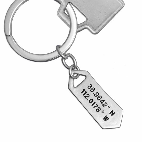 Sterling silver Hand stamped coordinates keychain on white background shown with key