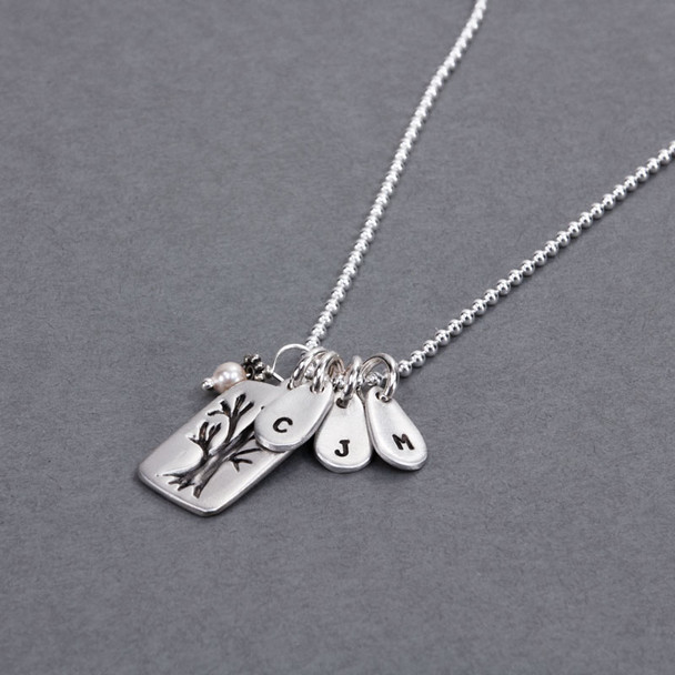 Side view of custom fine silver Family Tree necklace, personalized with hand stamped kids' initials, hung with pearl charm