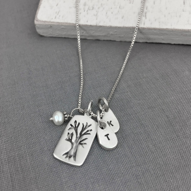 Custom fine silver Family Tree necklace, personalized with hand stamped kids' initials, hung with pearl charm, shown on gray