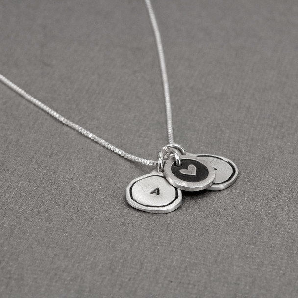 Tiny Framed Initial Charm Necklace made of fine silver, shown from the side