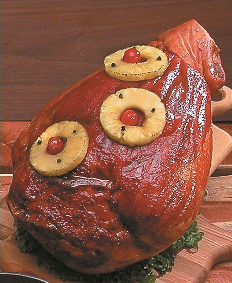 Hickory Smoked Sugar Cured Ham (Whole), cooked ham with pineapple rings and maraschino cherries on top, served on a wooden cutting board.