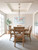 Timeless dining room with natural wood table, tray ceiling, chandelier, and world map wall art