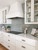 Classic blue and white kitchen with white range hood, blue tile backsplash, and glass-front cabinets