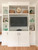 Custom white built-in media cabinet with under-cabinet lighting and styled grandmillennial shelf decor