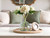 Styled coffee table with faux florals, jute tray, and green accents in a grandmillennial living room