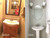 Before and after of a small powder room makeover, transforming a dark vanity into a bright pedestal sink and tile design