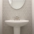 White pedestal sink against a patterned tile accent wall in a bright, updated powder room