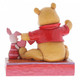 Disney Traditions Piglet and Winnie the Pooh sit close beside each other as they trace and snip a handmade garland of hearts figurine