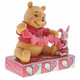 Disney Traditions Piglet and Winnie the Pooh sit close beside each other as they trace and snip a handmade garland of hearts figurine