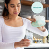 Mother pumping with Aura Glow while sleeping baby lies nearby, nightlight illuminating collection container