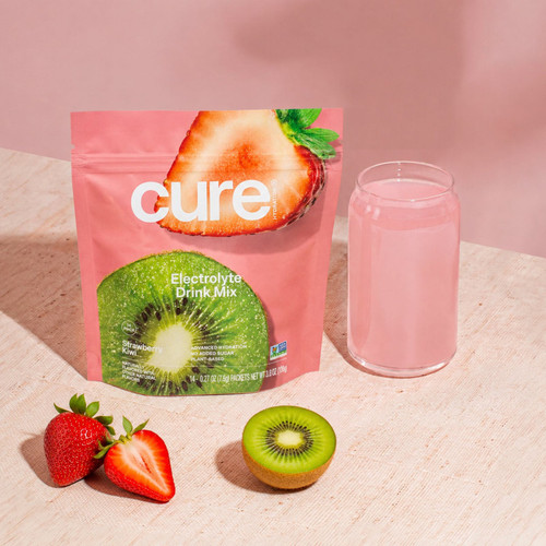 Pouring Strawberry Kiwi Cure powder into a glass of water