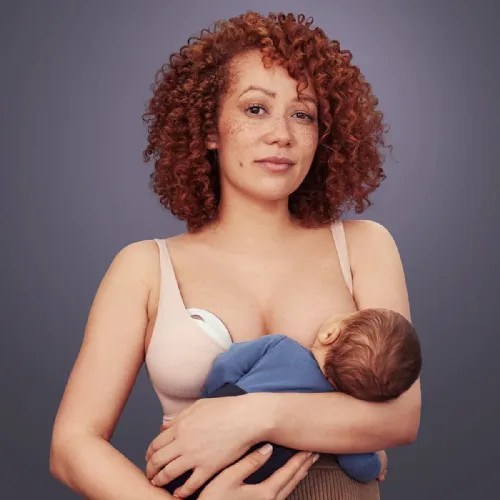 Mother wearing Elvie Curve while nursing baby on other side to catch letdown