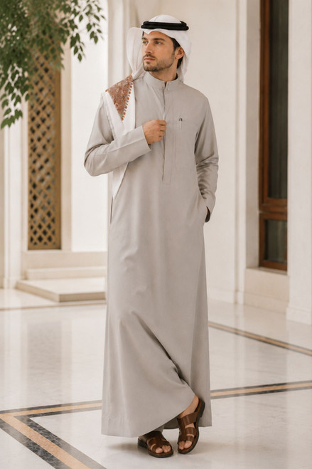 Man wearing a traditional saudi thobe in an indoor setting with decorative elements.