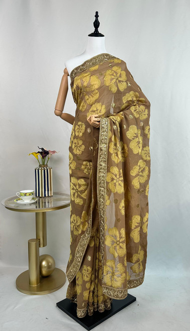 Luxurious Taupe Organza Saree with Golden Floral Motifs & Embroidered Border Luxurious Taupe Organza Saree with Golden Floral Motifs & Embroidered Border