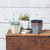 Different colored resin planters on a rustic side table with some stacked and two planted