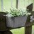 Gray wall planter with white flowers mounted to a fence gate