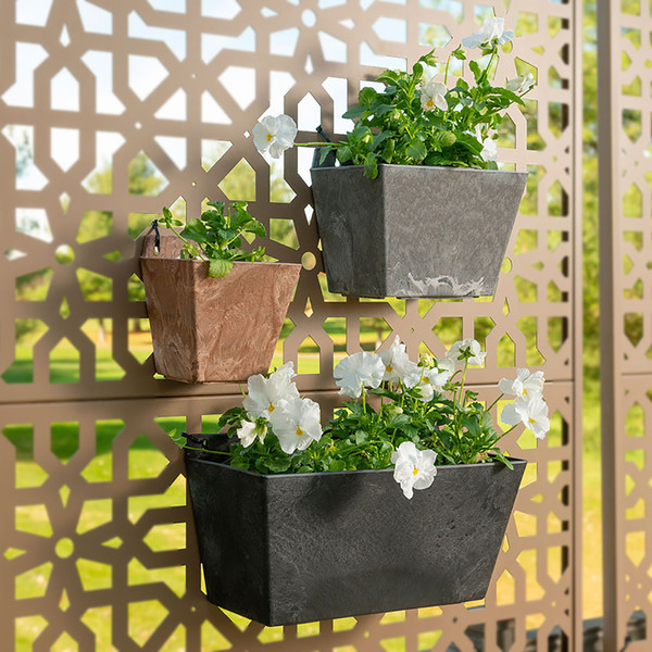 Three wall planters with white flowers mounted to outdoor decor