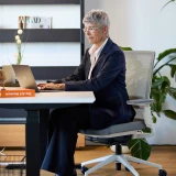 Une femme d’affaires sur ordinateur portable à un bureau réglable en hauteur Elevate