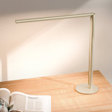 Lampe de bureau ofinto Lumino Desk sable avec base – lampe LED sur un bureau en bois avec un magazine ouvert ; éclairage de poste de travail moderne et minimaliste