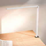 Lampe de bureau ofinto Lumino Desk blanche avec pince de table noire (en option) – lampe LED sur un bureau en bois avec un magazine ouvert ; éclairage de poste de travail moderne et minimaliste