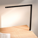 Lampe de bureau ofinto Lumino Desk noire avec pince de table blanche (en option) – lampe LED sur un bureau en bois avec un magazine ouvert ; éclairage de poste de travail moderne et minimaliste