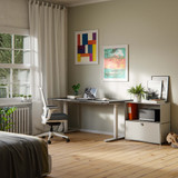 Commode Cubox à abattant en gris soie à côté d'une table de travail dans un home office lumineux avec parquet