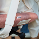 Chaise de bureau ofinto Cloud rouge, gros plan de l’accoudoir et du rembourrage de l’assise avec le logo ofinto