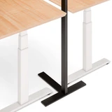 Pied en T du lampadaire ofinto Lumino sous le bureau Elevate – gros plan des pieds noirs avec revêtement antidérapant sous le bureau assis-debout ; intégration peu encombrante de l’éclairage et du poste de travail ergonomique