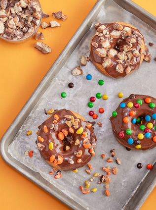 The image is of a tray of donuts. It features various types of donuts on a baking sheet, showcasing a variety of flavors and textures. The donuts seem freshly baked and are ready to be enjoyed as a snack or dessert.