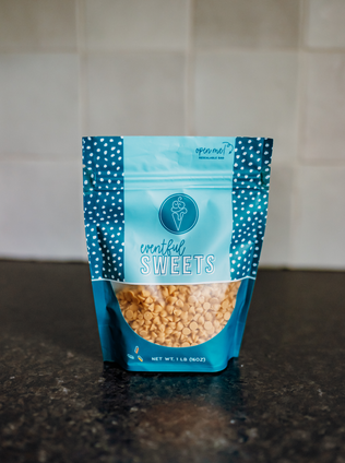 The image shows a resealable bag of "Eventful Sweets," which appears to contain small peanut butter chips. The bag is predominantly blue with a lighter blue panel in the center and darker blue sides featuring white polka dots. At the top of the bag, there is a label that says "open me! RESEALABLE BAG." Below the label, there is a logo with an ice cream cone and the initials "ES" inside it. The name "Eventful Sweets" is printed below the logo. The bottom part of the bag is transparent, allowing the contents to be visible. The net weight is listed as 1 lb (16 oz).