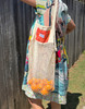 A raw cotton string bag with a vintage kantha design, on the shoulder and showing the length of the bag when carrying produce.
