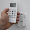 Hand holding remote with wall mounted holder.