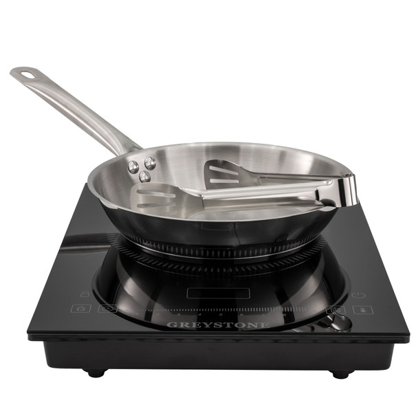 RV induction portable cooktop with stainless steel pan and tongs on top.