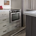 Stainless steel range in white cabinets and countertop inside of an RV.