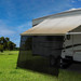 RV awning sun shade installed on an awning on a RV in a field.