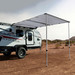 Trailer with awning extended parked in a desert.