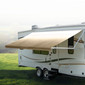 Tan awning extended out on an RV in a clearing.