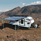 Trailer with awning extended in front of a canyon.