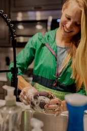 woman washing coffee mug in sink