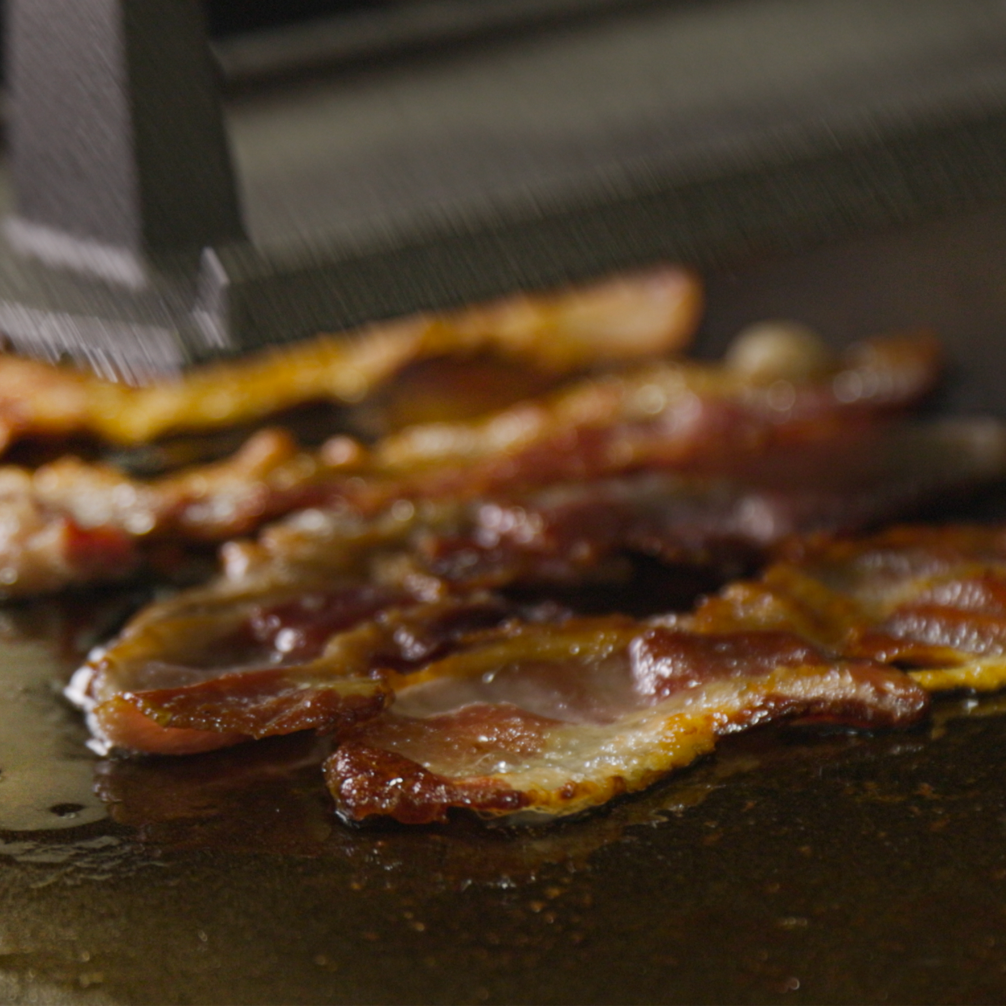 Bacon being cooked on the griddle.