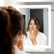 Isabel putting lipstick on in lighted mirror