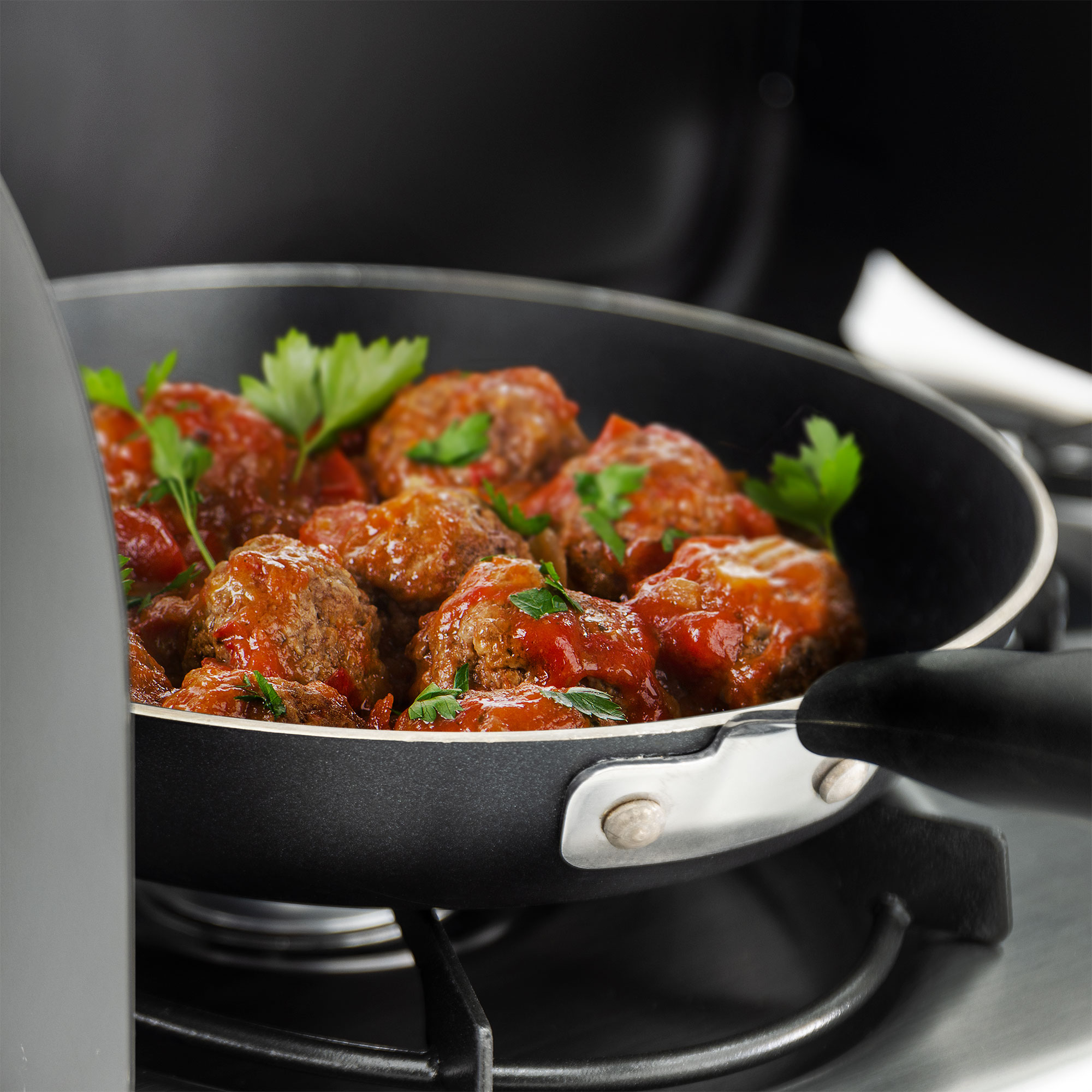 Meatballs cooking in a pan on the cooktop. Meatballs cooking in a pan on the cooktop.