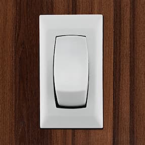 White RV single pole double throw switch installed on a wood wall.