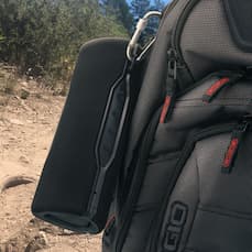 portable bluetooth speaker clipped to backpack