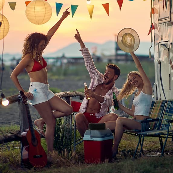 group of people cheering and dancing around portable bluetooth speaker