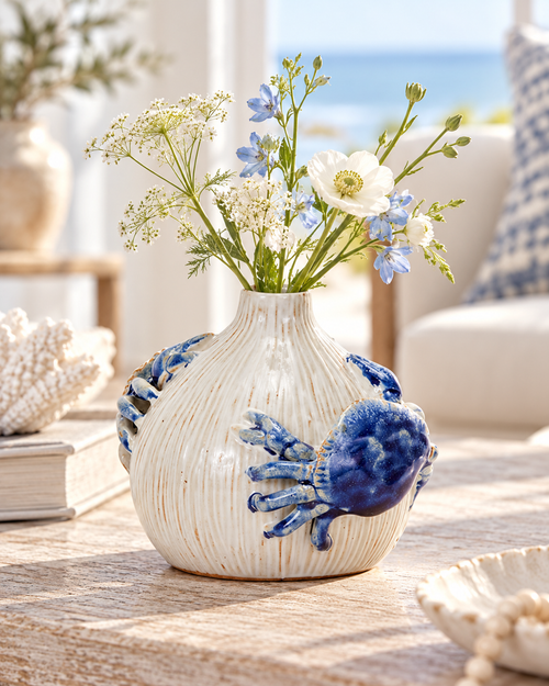 White and ocean blue sea crab ceramic vase styled with delicate flowers in a coastal interior