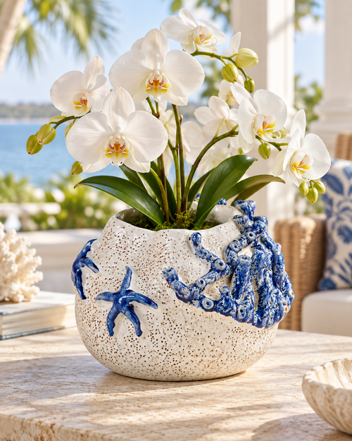 White and cobalt blue sea life ceramic vase styled with orchids in an upscale coastal interior