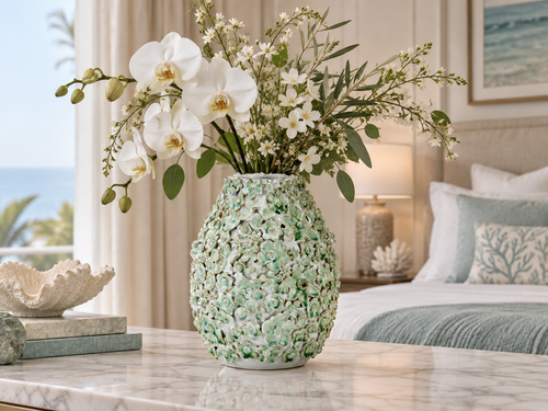 Handmade Thai green floral ceramic vase with orchids and airy greenery in an elegant coastal room