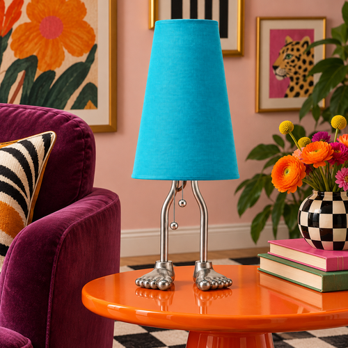 Adam turquoise cotton-shade table lamp with sculptural silver metal feet on an orange side table beside plum seating in an eclectic room.