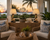 Pier Twist abaca rope table lamp L132 styled in a tropical lanai with natural woven furniture, greenery and warm ambient lighting.